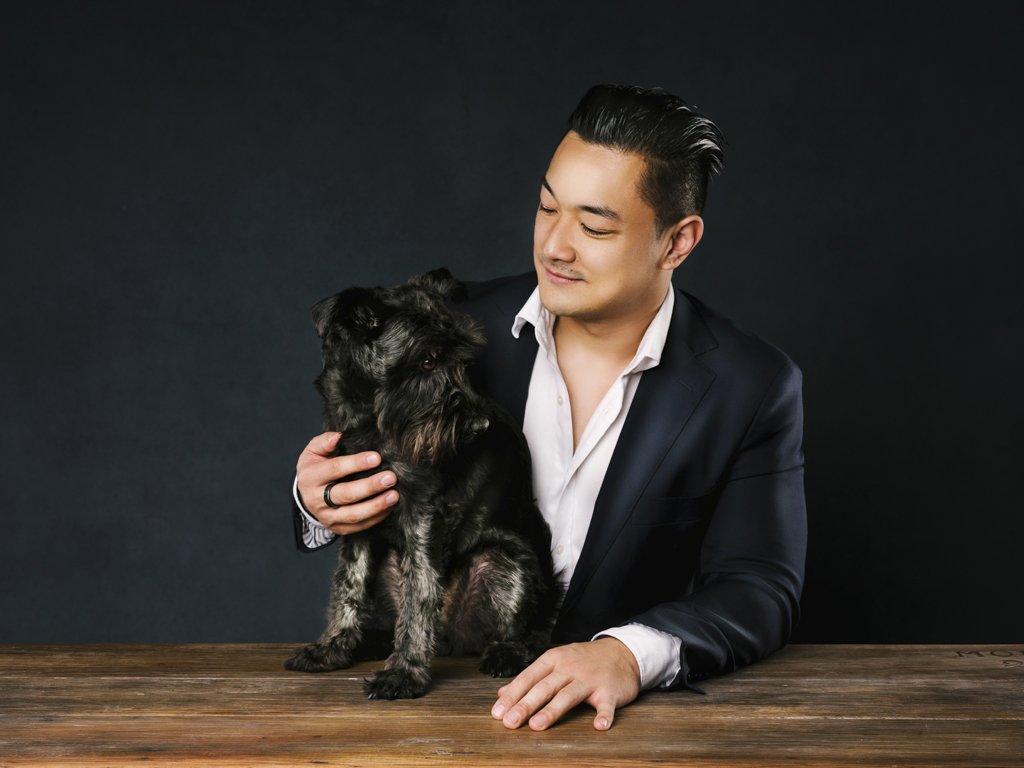 Man in suit with black dog on table